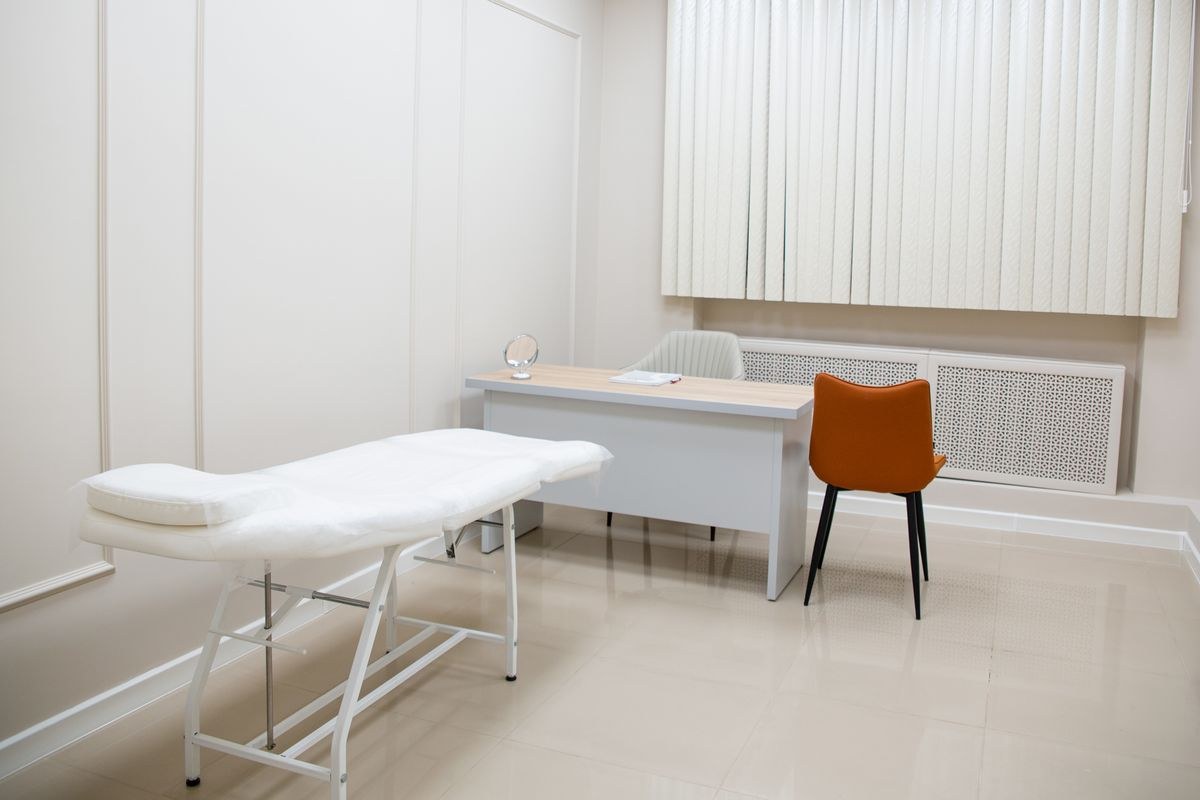 Medical consultation room with examination bed, desk and chairs